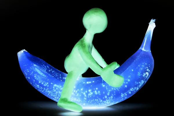Shaded puppet of plasticine riding on banana — Stock Photo, Image