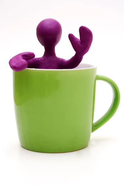Purple puppet of plasticine signing from cup — Stock Photo, Image