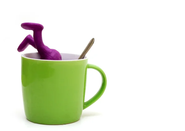 Purple puppet of plasticine sinking in cup — Stock Photo, Image