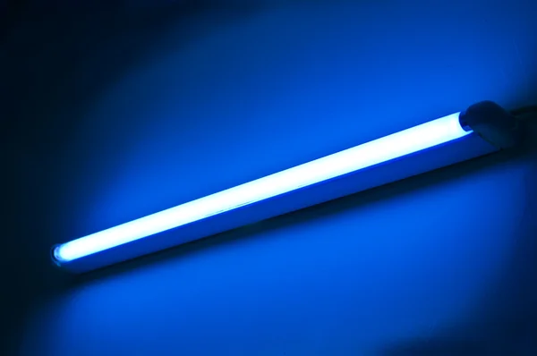 Lâmpada fluorescente brilhando na parede de cor azul — Fotografia de Stock