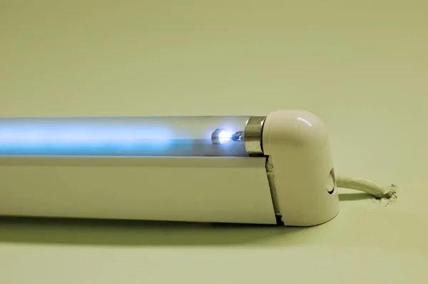 Флуоресцентная лампа, сияющая на белом студийном фоне — стоковое фото