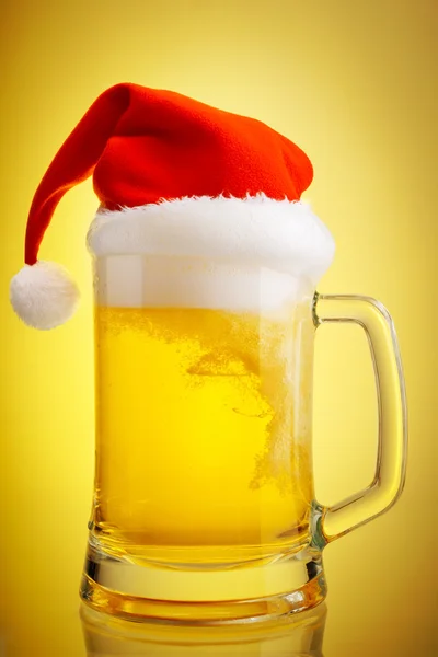 Cerveja e chapéu de Papai Noel em um fundo amarelo — Fotografia de Stock