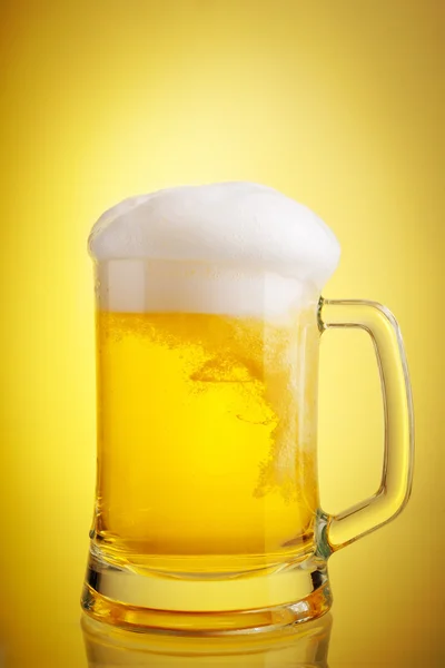 Glass of beer close-up with froth over yellow background Stock Picture