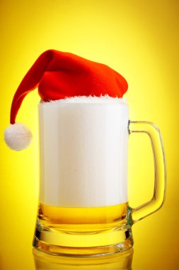 Beer and hat of Santa Claus on a yellow background clipart