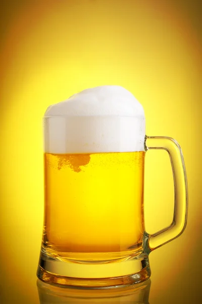 Glass of beer close-up with froth over yellow background — Stock Photo, Image