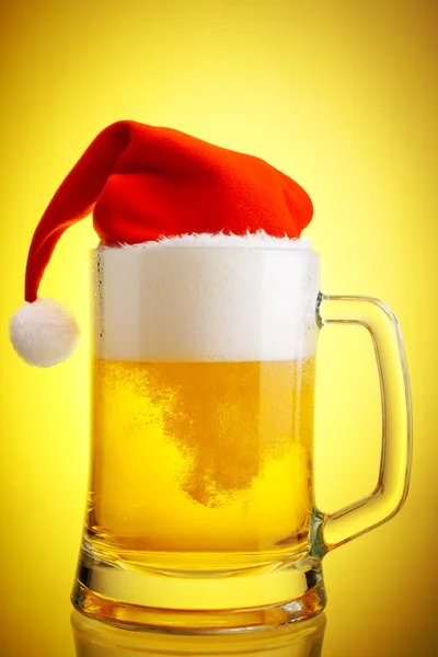 Cerveza y sombrero de Santa Claus sobre fondo amarillo — Foto de Stock
