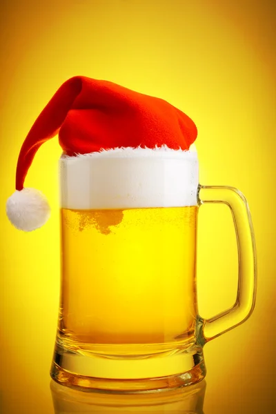 Cerveza y sombrero de Santa Claus sobre fondo amarillo — Foto de Stock