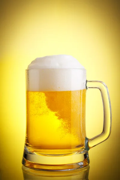 Glass of beer close-up with froth over yellow background Stock Photo