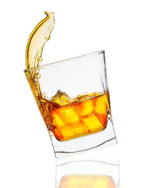 Glass of whiskey with ice cubes splashing out over white — Stock Photo, Image