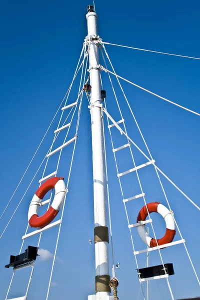 Sailing mast with life buoy over blue sky — Stock Photo, Image