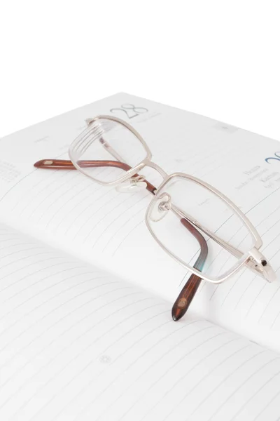 Glasögon i en öppen dagbok — Stockfoto