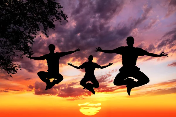Saltando silhuetas de Yoga em lótus — Fotografia de Stock