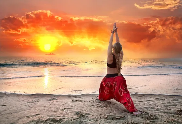 Yoga virabhadrasana guerreiro pose ao pôr do sol — Fotografia de Stock