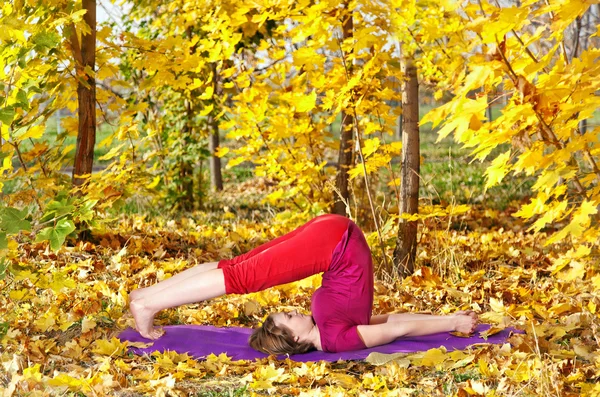 Yoga halasana in autumn — Stock Photo, Image