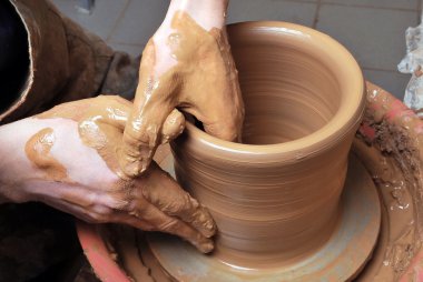 Hands of a potter, creating an earthen jar on the circle clipart