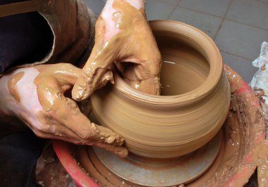 Hands of a potter, creating an earthen jar on the circle clipart