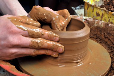 Hands of a potter, creating an earthen jar on the circle clipart