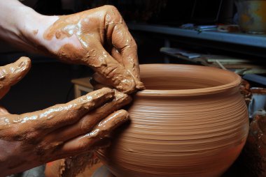 Hands of a potter, creating an earthen jar on the circle clipart