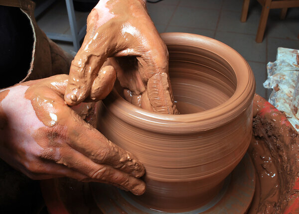 Hands of a potter, creating an earthen jar on the circle