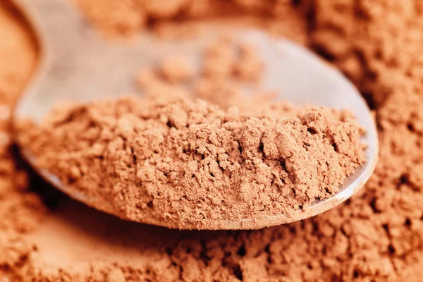 Cocoa powder and steel spoon — Stock Photo, Image
