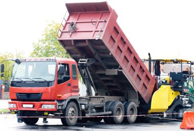 Dumptrack and asphalt spreading machine working on road clipart