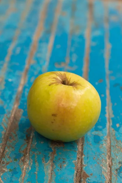 Žlutá šťavnaté jablko na modré dřevěné plochy — Stock fotografie