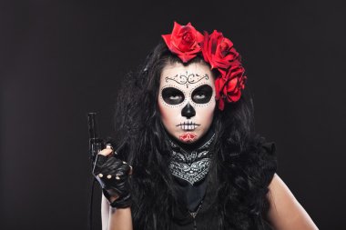 Serious woman in day of the dead mask with gun