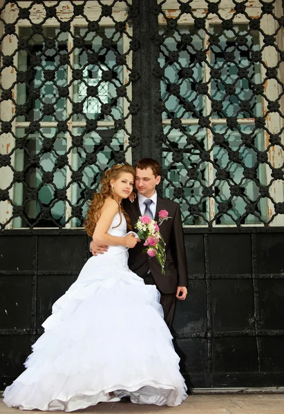 Boda joven pareja de pie cerca de enorme puerta — Foto de Stock