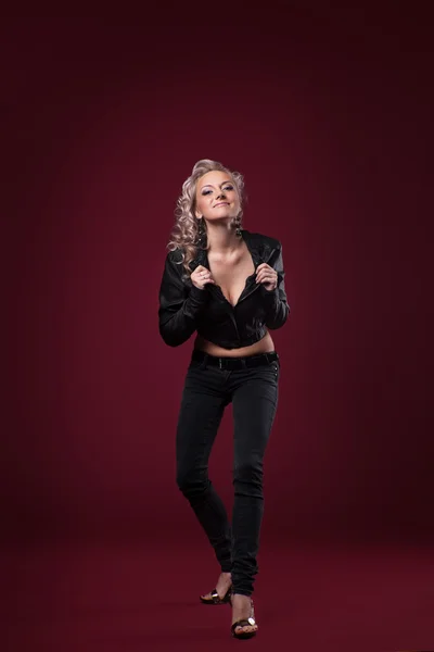 Beauty woman posing in sexy leather jacket on red — Stock Photo, Image