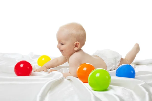 Bonito bebê jogar na cama com bolas de cor — Fotografia de Stock