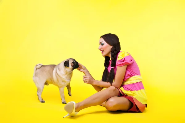 Pin-up girl in doll dress feed a dog with cheese — Stock Photo, Image