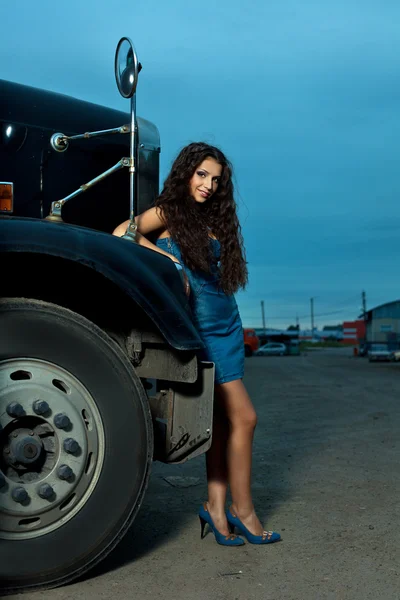 Young pretty girl posing before huge cargo truck — Stock Photo, Image