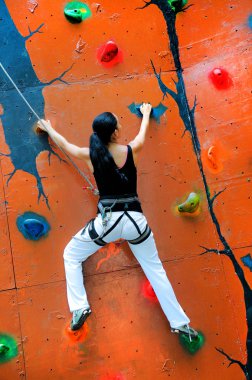 Girl climbing on a climbing wall clipart