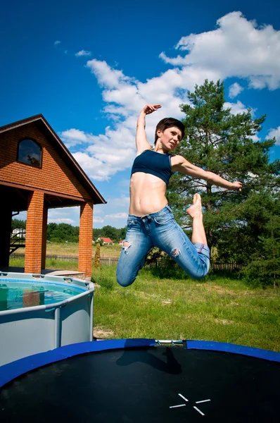 Girl jumps on a trampoline — Stok fotoğraf