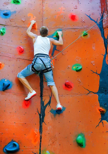 Homem escalando em uma parede de escalada — Fotografia de Stock