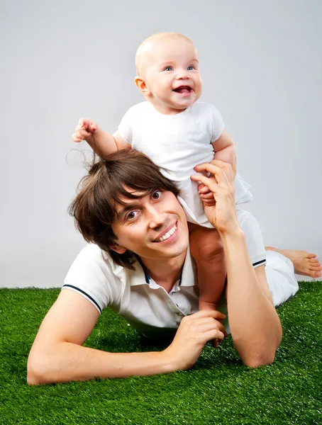 Vader met een baby liggend op gras — Stockfoto
