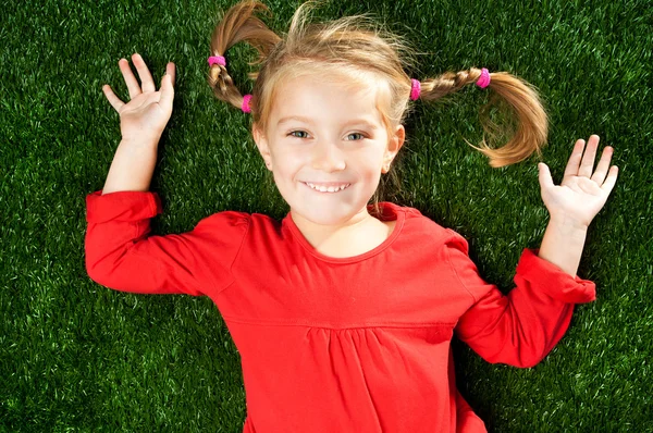 Μικρό κορίτσι χαμογελά στο γρασίδι — Φωτογραφία Αρχείου