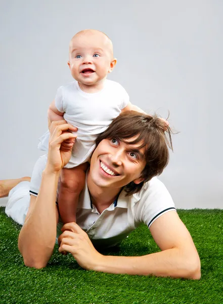 Padre con un bambino sdraiato sull'erba — Foto Stock