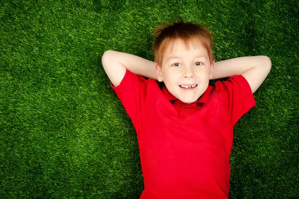 緑の芝生の上に横たわる少年 — ストック写真