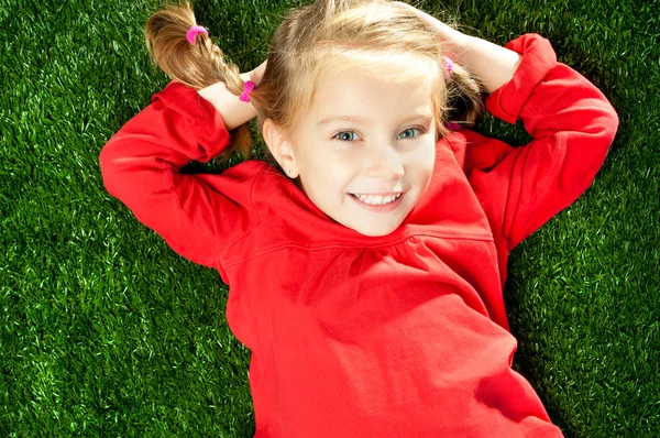 Liten flicka leende på gräs — Stockfoto