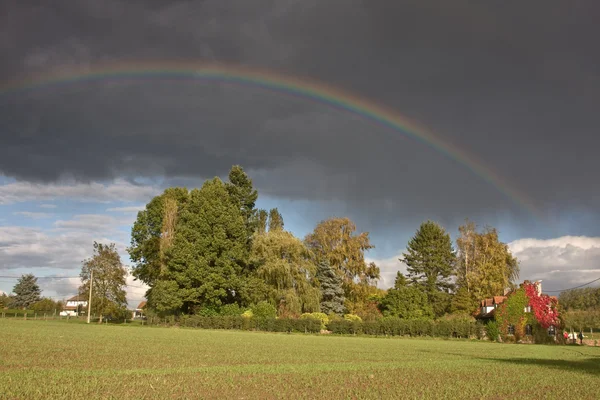 Arcobaleno e pioggia su un campo — Foto Stock