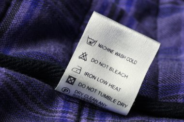 Laundry care label on scotch textile background clipart