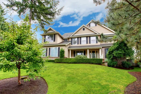 Frente a la gran casa beige con hierba verde y árboles — Foto de Stock