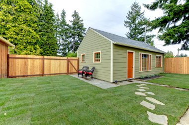 Small green guest houe in the fenced back yard. clipart