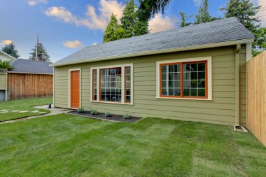 Small green guest house in the fenced backyard. clipart