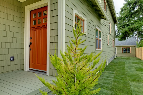 Передні помаранчеві двері зеленого будинку  . — стокове фото