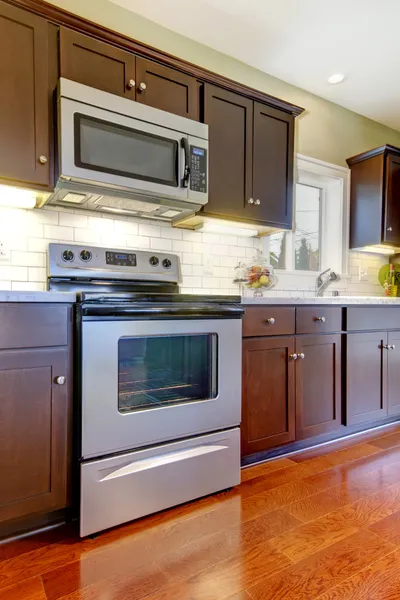 Kompor dapur coklat modern dan microwave dengan lantai ceri . — Stok Foto