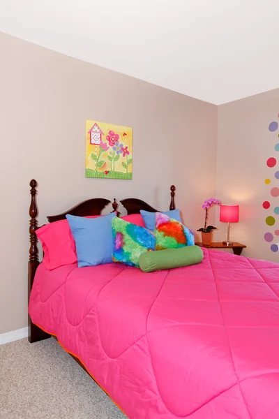 Girls pink bed with colorful pillows — Stock Photo, Image