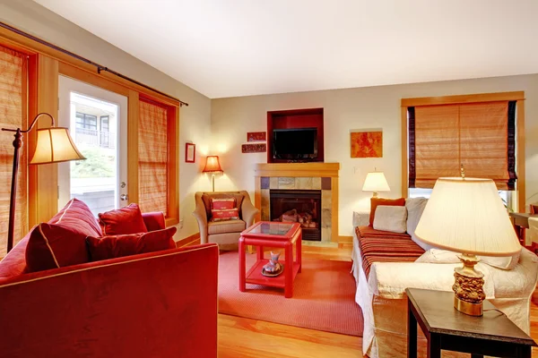 Útulný obývací pokoj s červenou pohovku a krb — Stock fotografie