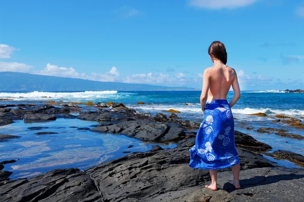Young women is looking at the ocean on the lava rocks. — Stock Photo, Image